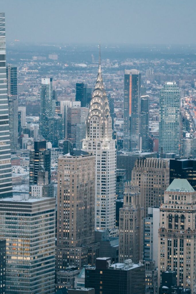 Modern skyscrapers located on streets in financial district against cloudless sky and residential houses in contemporary megapolis against cloudless sky